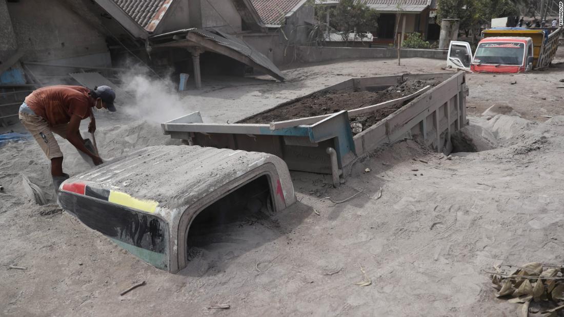 火山灰に埋もれたトラックを点検する男性/Trisnadi/AP