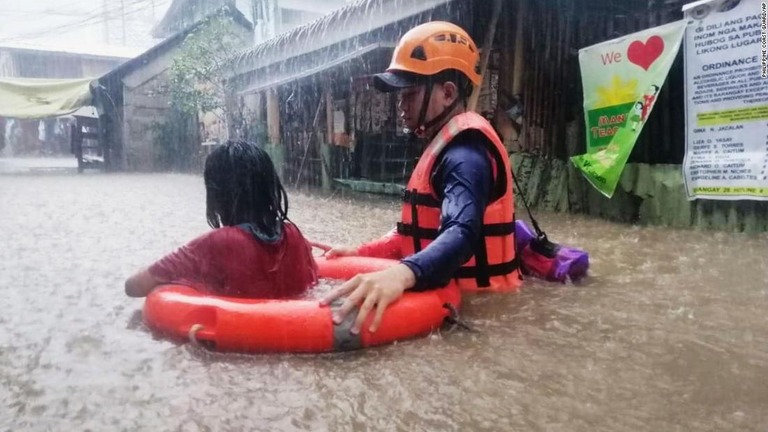 冠水した道路での移動を助ける沿岸警備隊員＝１６日、フィリピン・カガヤンデオロ/Philippine Coast Guard/AP