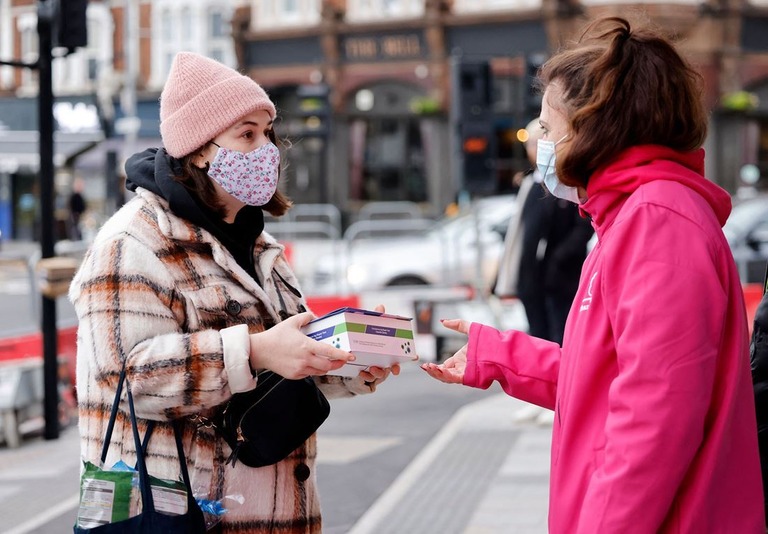 ロンドン北東部でボランティアが新型コロナの検査キットが入った箱を手渡す/Tolga Akmen/AFP/Getty Images