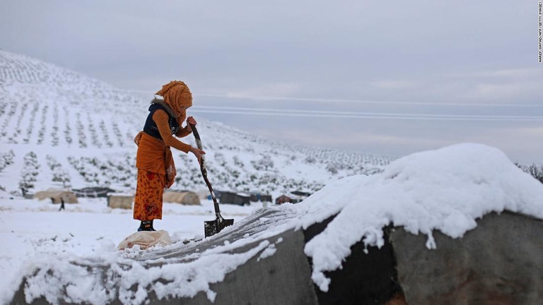 テントの雪かきをする女性＝シリア・ラジュのキャンプ/Aaref Watad/AFP/Getty Images