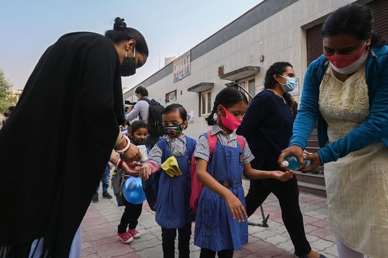 印ニューデリーの学校で教室に入る前に手指消毒や検温を行う児童ら＝２０２１年１１月/Money Sharma/AFP via Getty Images
