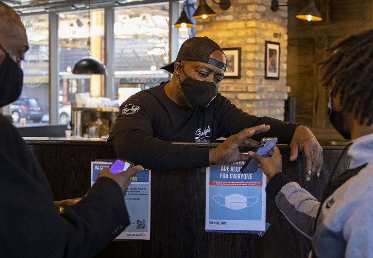 米シカゴのレストランで入店時の健康チェックを行う男性従業員と利用客/Brian Cassella/Chicago Tribune/Tribune News Service/Getty Images