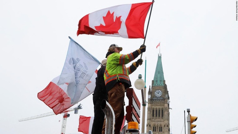 国会議事堂前で国旗を振るデモ参加者＝６日、オタワ/Patrick Doyle/Reuters