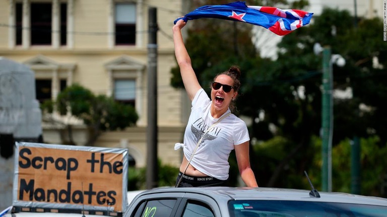 車の後部座席から国旗を振って抗議するデモ参加者/Hagen Hopkins/Getty Images
