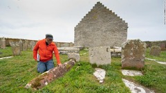ガイドを務めるジョナサン・フォードさんが同教会の風変わりな墓石について説明する