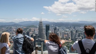 マレーシアの首都クアラルンプールの超高層ビル群を眺める観光客ら