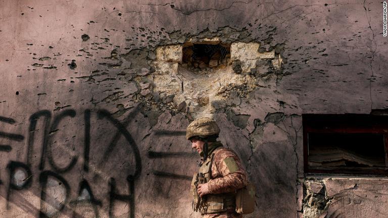 ウクライナ東部の最前線の町クリムスケで迫撃砲の攻撃を受けた建物に沿って歩くウクライナ軍兵士＝１９日/Vadim Ghirda/AP