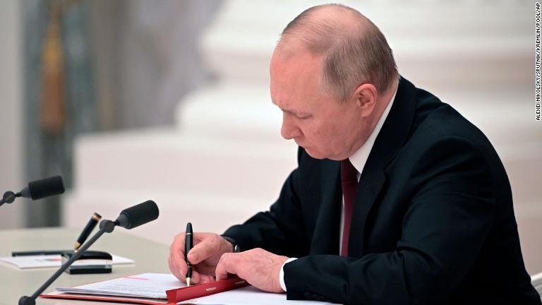 「ドネツク人民共和国」と「ルガンスク人民共和国」を承認する法令に署名するプーチン大統領。同日早く、２地域のトップはプーチン氏に独立と主権の承認を求めていた。プーチン氏の安全保障会議のメンバーはそれに賛成した＝２１日/Alexei Nikolsky/Sputnik/Kremlin/Pool/AP