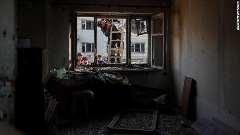 ドネツク地方の最前線ノボルハンスケ付近で２２日に砲撃があり、被害を受けた民家で作業する人々/Gleb Garanich/Reuters