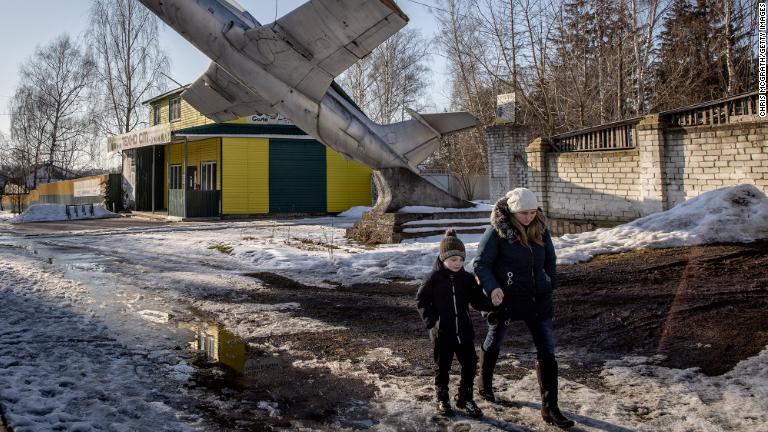 ウクライナ・ロシア・ベラルーシの３カ国の国境に近いウクライナ・センキフカ。軍のモニュメントの下を歩く女性と子ども＝１４日/Chris McGrath/Getty Images