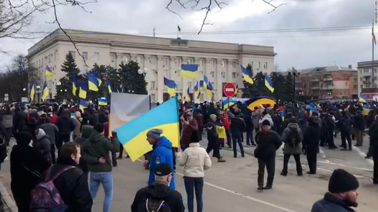 ヘルソン市内でウクライナの国旗を振るなどして抗議する人々/Obtained by CNN
