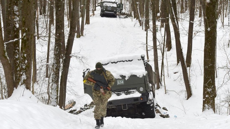 ハリコフ周辺の森で破壊されたロシア軍車両を横切るウクライナ領土防衛軍の兵士＝７日/Sergey Bobok/AFP/Getty Images