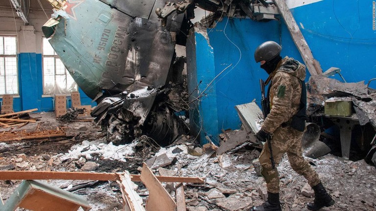 ロシア軍爆撃機の残骸が見える損壊した建物の中を歩くウクライナ軍兵士/Andrew Marienko/AP