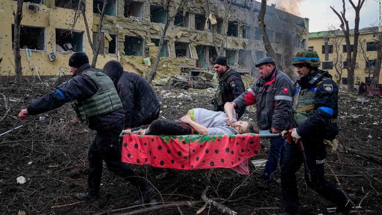 負傷した妊婦の女性を運ぶウクライナの救急隊員とボランティア＝９日、ウクライナ・マリウポリ/Evgeniy Maloletka/AP