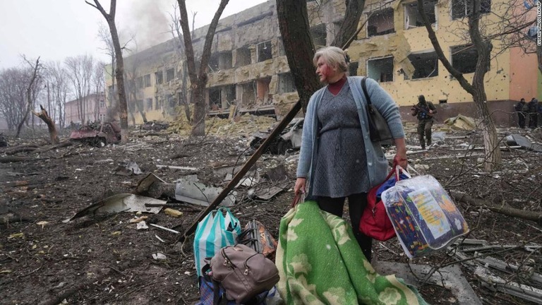 爆撃を受けた病院の外に立つ女性＝９日、ウクライナ・マリウポリ/Evgeniy Maloletka/AP