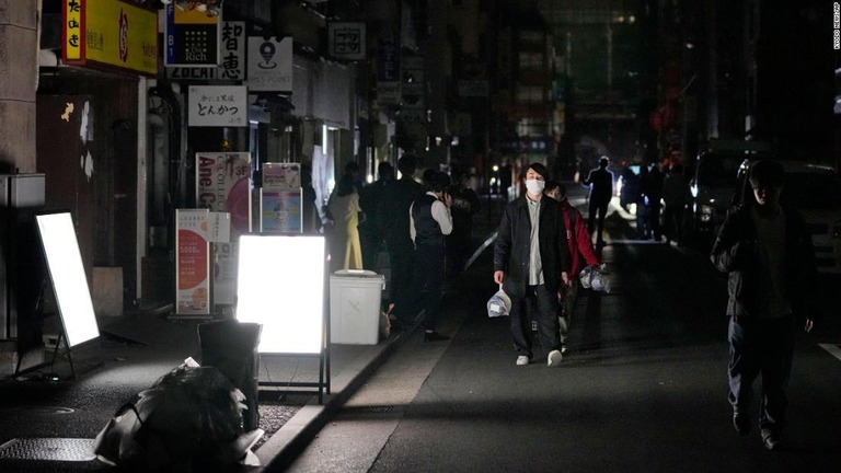 暗くなった街中を移動する人々/Kyodo News/AP