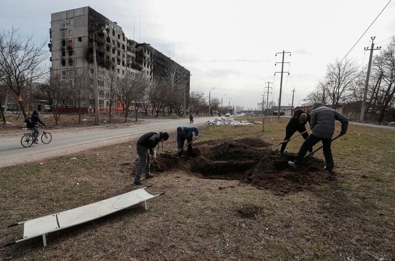 犠牲者のための墓穴を掘る人々＝２０日、ウクライナ・マリウポリ/Alexander Ermochenko/Reuters