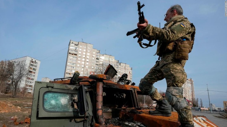 最近の戦闘で破壊された装甲兵員輸送車の上に立つウクライナ軍の兵士＝２６日、ハリコフ/Efrem Lukatsky/AP