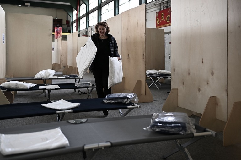 フランス南西部ボルドーの公共体育館でベッドの上に枕を置く女性＝２５日/Philippe Lopez/AFP/Getty Images