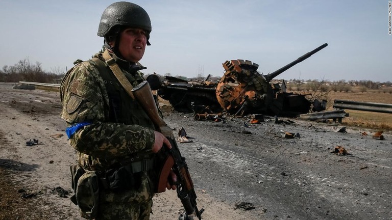 破壊されたロシア軍の戦車の近くに立つウクライナ軍兵士＝２８日、ウクライナ首都キエフ近郊/Gleb Garanich/Reuters