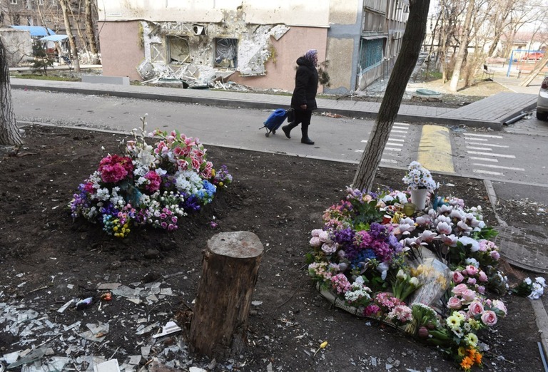 マリウポリの戦闘で死亡した住民の墓地の横を歩く女性＝３日/Stringer/Reuters