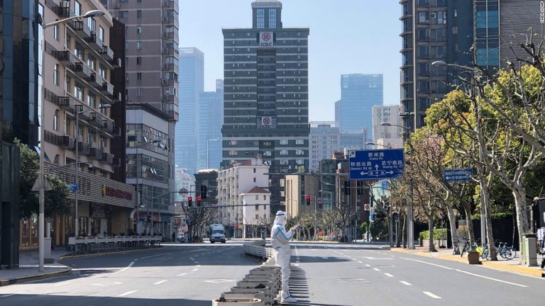 人通りの絶えた道路の真ん中に立つ作業員/Chen Si/AP