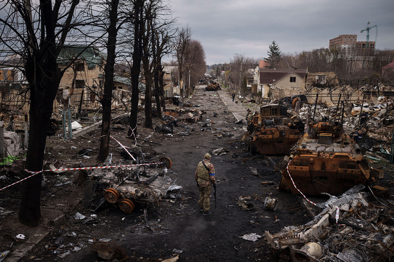 首都近郊の町ブチャで、破壊されたロシア軍の戦車の近くを歩くウクライナ軍の兵士/Felipe Dana/AP