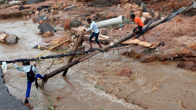 橋が流され、即席の橋を人々が渡る＝１２日、ンツズマ/Str/AP