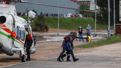 ウムラジ付近で浸水した仕事場から救出された男性が救助隊員とともに歩く＝１２日