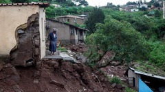 豪雨で洪水被害のあった南アフリカ・ダーバン。自宅の玄関前に立つ女性＝１２日
