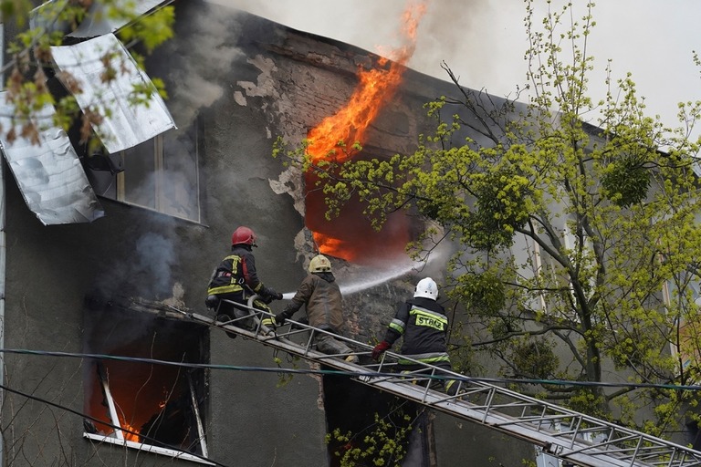 ロシア軍の攻撃後、集合住宅で消火活動を行う消防士ら＝１７日、ハルキウ/Andrew Marienko/AP