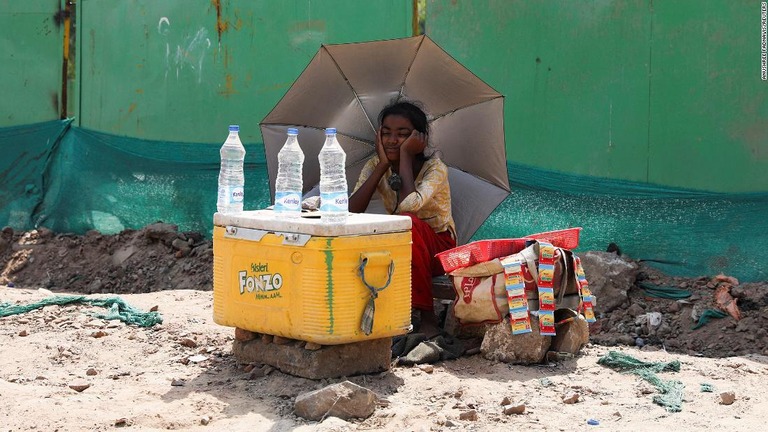 傘を使って身を守りながら水を売る少女＝インド・ニューデリー/Anushree Fadnavis/Reuters