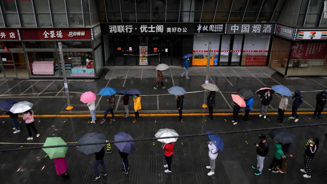 ロックダウン対象となった北京の住民がコロナ検査のため雨の中並ぶ＝２７日/Andy Wong/AP