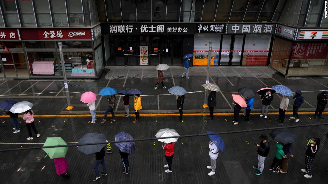 ロックダウン対象となった北京の住民がコロナ検査のため雨の中並ぶ=27日/Andy Wong/AP