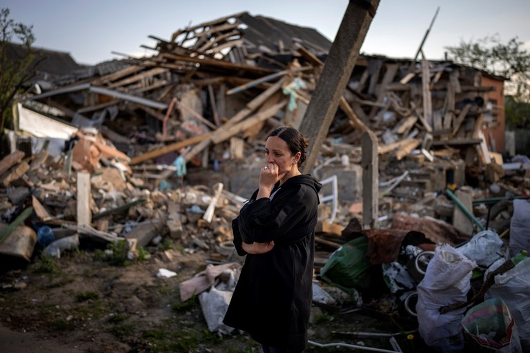 ３月下旬の爆撃で破壊されたイルピンの自宅前で佇む女性/Emilio Morenatti/AP Photo