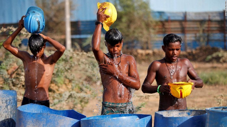 ヘルメットを使って体に水をかけ暑さをしのぐ作業員ら＝インド/Amit Dave/Reuters