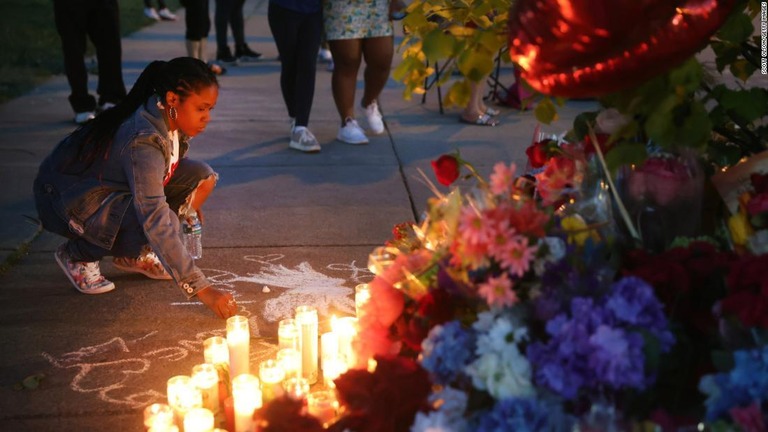 銃撃現場となったスーパーマーケットの外で、地面にメッセージを書く女性/Scott Olson/Getty Images