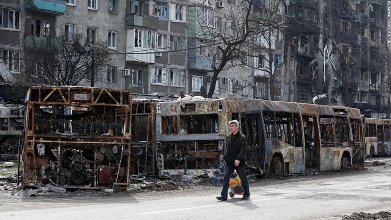 焼け焦げたバスの前を歩くマリウポリの地元住民/Alexander Ermochenko/Reuters