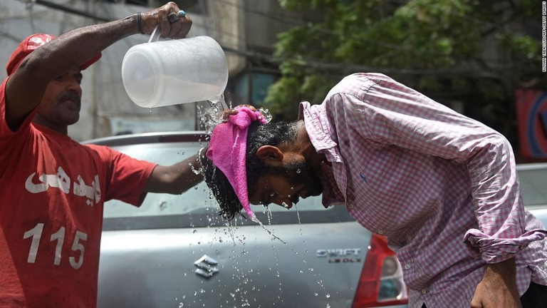 暑さをしのぐために歩行者に水をかけるボランティア＝１６日、パキスタン・カラチ/RIZWAN TABASSUM/AFP/Getty Images