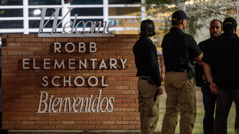 銃乱射事件の起きた小学校の前で言葉を交わす警官ら/Brandon Bell/Getty Images