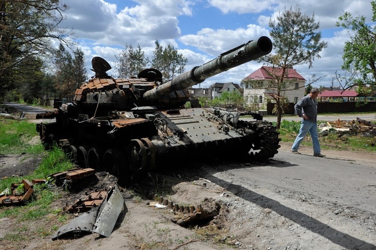 キーウ（キエフ）州の村の路上で、破壊されたロシア軍戦車の脇を歩く男性/Sergei Chuzavkov/SOPA Images/LightRocket/Getty Images