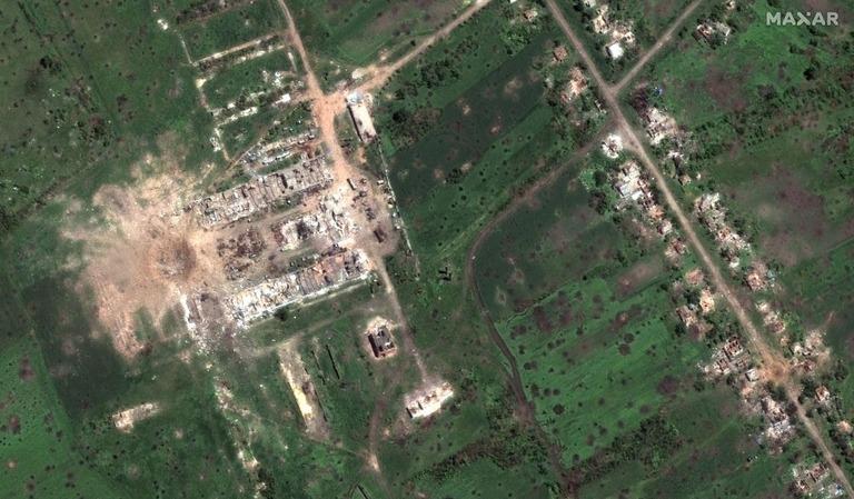 巨大なクレーターを捉えた衛星画像。近くには破壊された建物群の跡が見える/Satellite image ©2022 Maxar Technologies