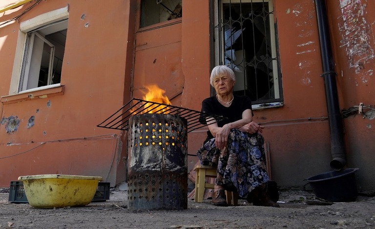 マリウポリ市内にある家屋の庭で調理する女性/AFP/Getty Images