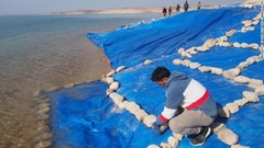 水による腐食を防ぐため、遺跡をビニールシートで覆う研究員