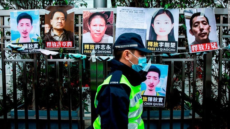 中国の人権活動家の釈放を求めるプラカード前を通る警察官＝２０２０年２月１９日、香港/Isaac Lawrence/AFP/Getty Images