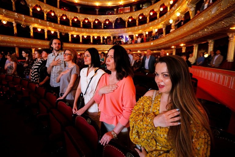 侵攻後初となる歌劇場での公演で、起立し、ウクライナ国歌を斉唱する観客ら/NurPhoto/Getty Images