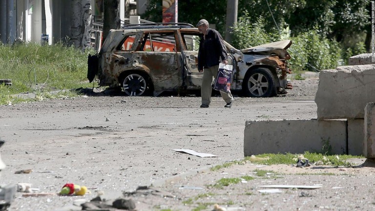 ウクライナ東部のリシチャンスクで破壊された車両の前を横切る男性/ANATOLII STEPANOV/AFP/AFP via Getty Images