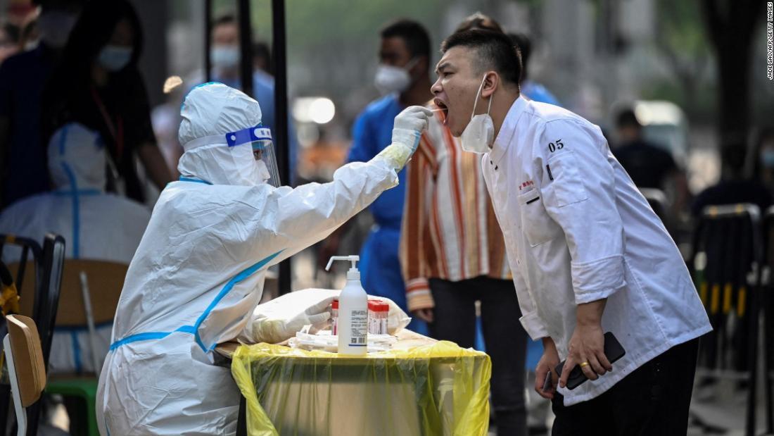 男性の口から綿棒でサンプルを採取する医療従事者＝１５日、中国・北京にあるショッピングモール外の検査場
/Jade Gao/AFP/Getty Images