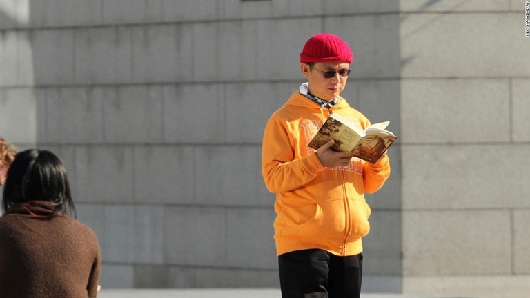 香港の国際金融センターの外で書籍を読む肖建華氏＝２０１３年１２月撮影/Next Magazine/AP