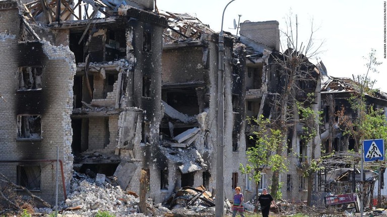 戦争で破壊されたウクライナ東部セベロドネツクの居住棟の前を歩く住人ら/ALEXANDER ERMOCHENKO/X03560/REUTERS